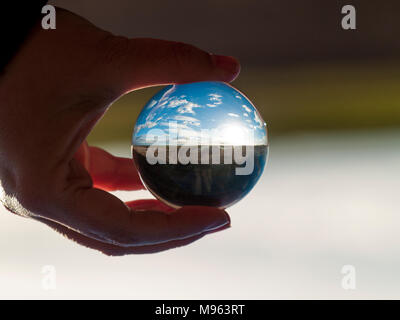 Woman hand holding bille de verre avec vue panoramique sur campagne et ciel bleu/ Concept pour l'environnement Banque D'Images