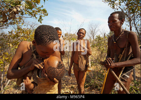 Ju/'hoansi bushmen San ou donner de l'eau mère bouche par la bouche à son bébé dans la brousse africaine, la Namibie, Grashoek Banque D'Images
