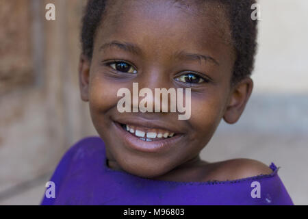 Souriante jeune fille en dehors de l'école dans village rural de Zanzibar Banque D'Images