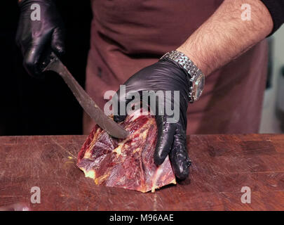 Les coupes d'un employé à un jamon jamon, stalle, jambon fumé espagnol décroche à la La Mercat de Sant Josep de la Boqueria, le centre de Barcelone, Espagne Banque D'Images