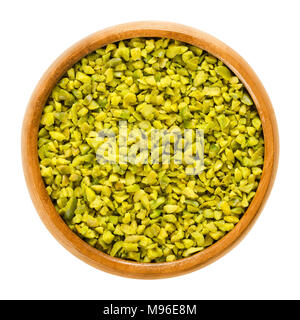 Pistaches vertes hachées dans un bol en bois. Les grains séchés et décortiquées. Fruits et graines décortiquées de Pistacia vera. Utilisé comme collation ou comme dessert. Banque D'Images