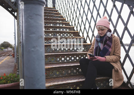 Femme assise sur un escalier et à l'aide de mobile phone Banque D'Images