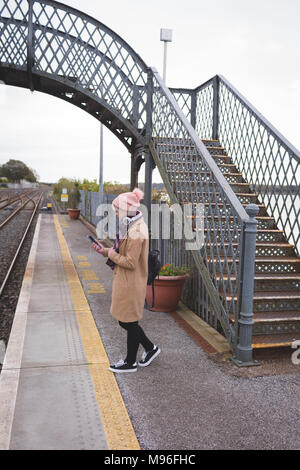 Femme à l'aide de téléphone mobile dans la plate-forme ferroviaire Banque D'Images