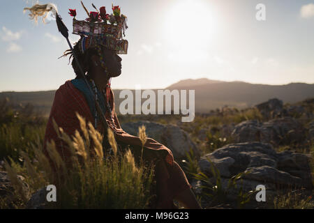 L'homme en costume traditionnel massaï assis à campagne Banque D'Images