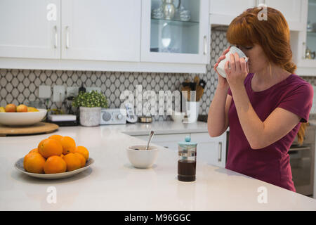 Femme ayant du café noir dans la cuisine Banque D'Images