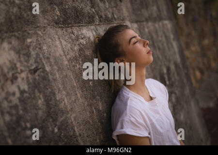 Woman leaning against wall dans la cour de tennis Banque D'Images