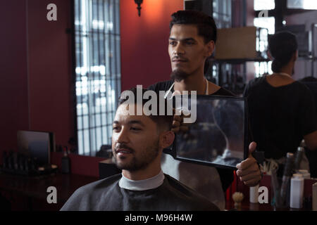 L'homme à sa nouvelle coupe de cheveux dans le miroir Banque D'Images