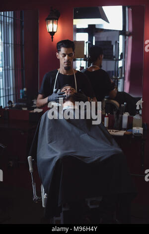 Coiffure L'application de la crème sur les clients beard Banque D'Images