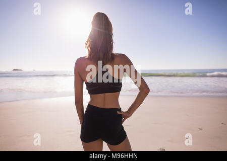 Fit woman standing with hand on hip dans la plage Banque D'Images