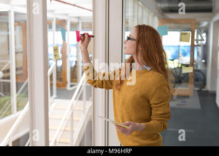 Female executive écrit sur les notes in office Banque D'Images