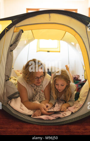 Mère et fille using digital tablet in tent Banque D'Images