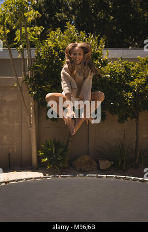 Fille sautant sur un trampoline dans le jardin Banque D'Images