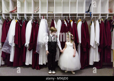 Boy and girl holding hands in front of choir robes Banque D'Images