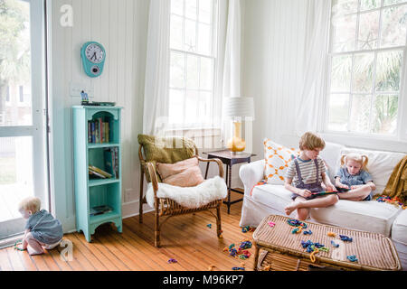 Boy and girl sitting on couch with baby next à porte Banque D'Images