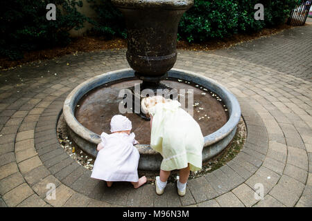 Bébé et les autres enfants jouant autour de fontaine Banque D'Images