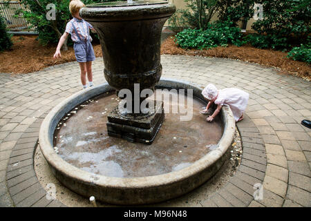 Bébé et les autres enfants jouant autour de fontaine Banque D'Images