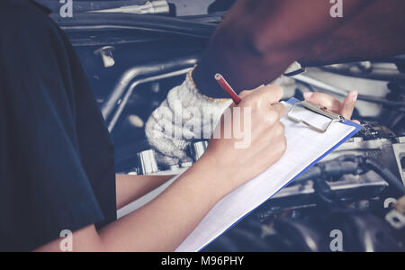 Les femmes asiatiques sont les ingénieurs et techniciens de contrôle et d'inspection mécanique sur une voiture en atelier de réparation automobile la liste au conseil Banque D'Images