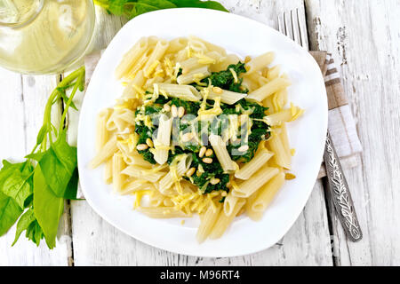 Pâtes penne aux épinards et noix de cèdre dans une assiette sur une serviette contre un feu de bois sur le dessus Banque D'Images