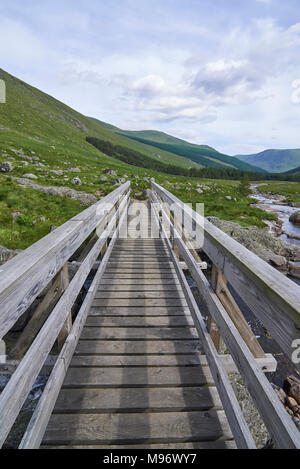 Une petite passerelle en bois sur le chemin d'Glen Doll dans les Angus Glens et parc national de Cairngorm dans les Highlands d'Ecosse. Banque D'Images