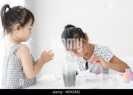 Happy Asian girl painting Easter eggs à la maison. Banque D'Images