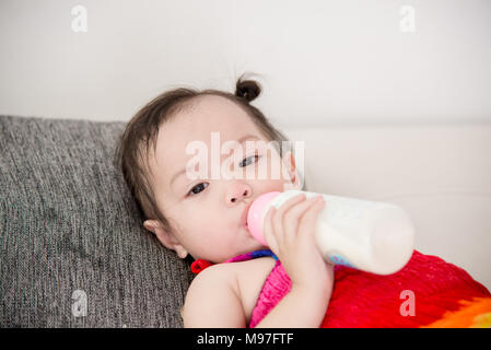 Bébé qui pleure avec une bouteille de lait à la maison. Banque D'Images