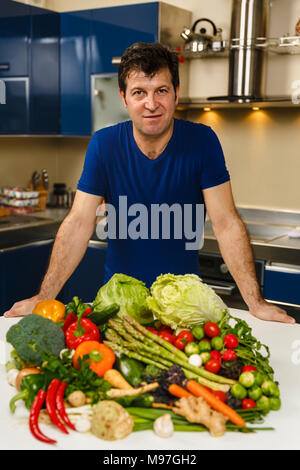 Homme avec une grande variété de légumes, prêts à être cuisinés Banque D'Images