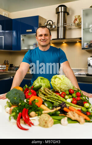 Homme avec une grande variété de légumes, prêts à être cuisinés Banque D'Images