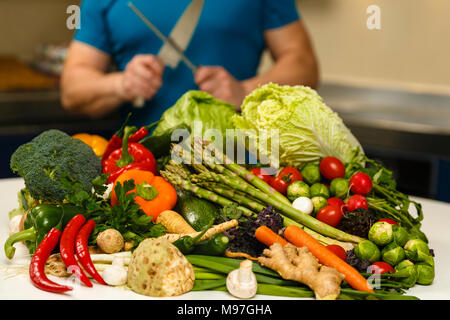 Homme avec une grande variété de légumes, prêts à être cuisinés Banque D'Images