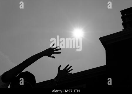 Woman's hand reaching out for the sun avec silhouette de bâtiment moderne Banque D'Images