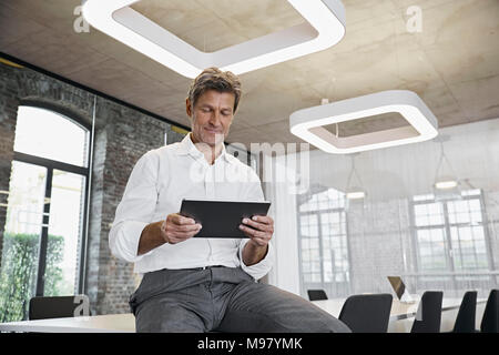 Mature businessman using tablet in modern office Banque D'Images