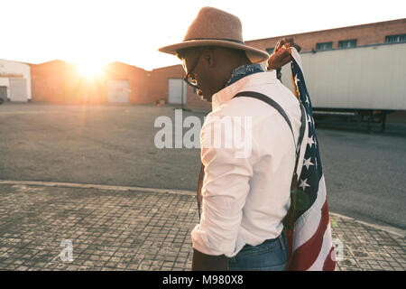 Jeune homme portant un chapeau et des lunettes holding American flag Banque D'Images