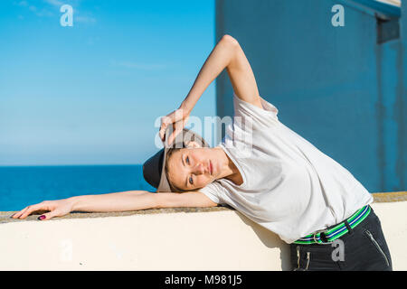 Portrait of woman wearing hat leaning on wall Banque D'Images