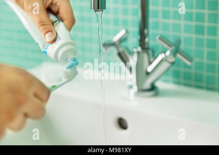 Mettre les mains du dentifrice sur une brosse à dents dans la salle de bains Banque D'Images