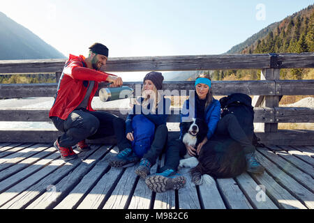 Groupe d'amis avec chien randonnées reposant sur un pont Banque D'Images