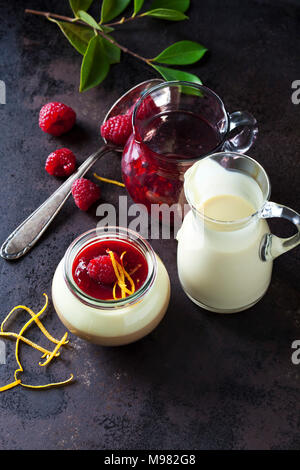 Verre de pudding avec de la sauce à la vanille et sauce aux framboises garnie de framboise et le zeste d'orange Banque D'Images