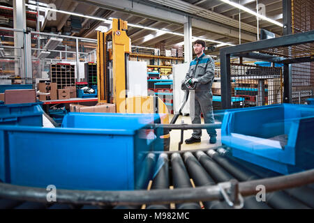 L'homme au travail en usine avec des cases sur la courroie du convoyeur Banque D'Images