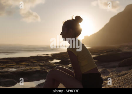L'INDONÉSIE, Bali, jeune femme assise sur la plage au coucher du soleil Banque D'Images