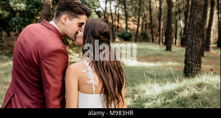 Vue arrière de Bride and Groom kissing in forest Banque D'Images