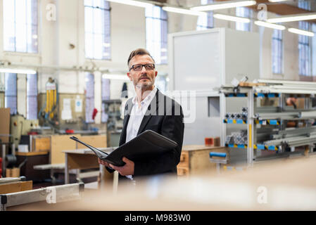 Mature businessman en usine holding folder Banque D'Images