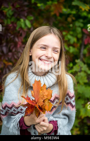 Portrait de fille qui rit, tas de feuilles d'automne Banque D'Images