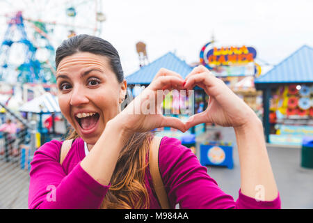 USA, New York, portrait de femme excité à Coney Island en forme coeur avec ses mains Banque D'Images