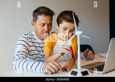 Père et fils avec l'ordinateur portable de l'assemblage du modèle d'éolienne Banque D'Images