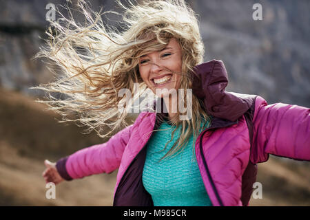 Happy young woman appuyé contre le vent dans les montagnes Banque D'Images