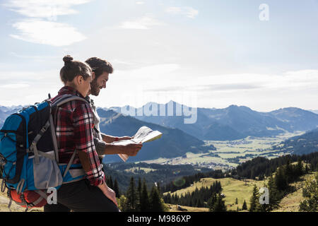 Autriche, Tyrol, young couple looking at map in mountainscape Banque D'Images