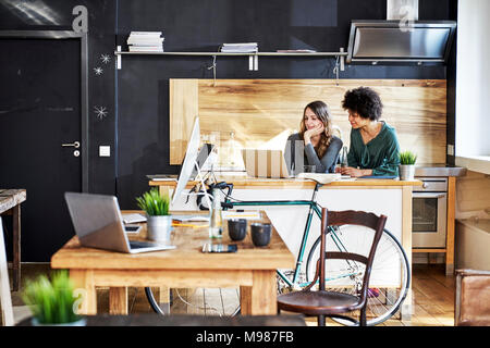 Deux jeunes femmes using laptop in modern office Banque D'Images