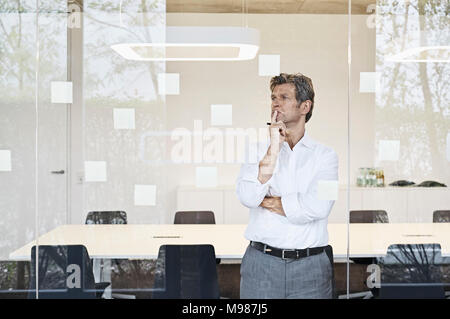 Mature businessman looking at sticky notes à du verre dans la salle de conférence moderne Banque D'Images