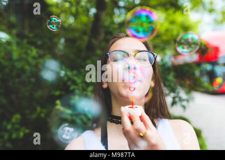 Teenage girl blowing soap bubbles outdoors Banque D'Images