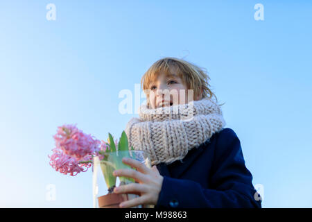 Portrait of happy boy avec des jacinthes en pot contre le ciel bleu Banque D'Images