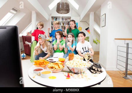 Groupe d'enfants regarder le soccer world championship avec une table pleine de bonbons et collations Banque D'Images