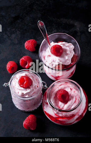 Peu de crème fouettée avec fraises et sauce aux fraises dans différents verres Banque D'Images